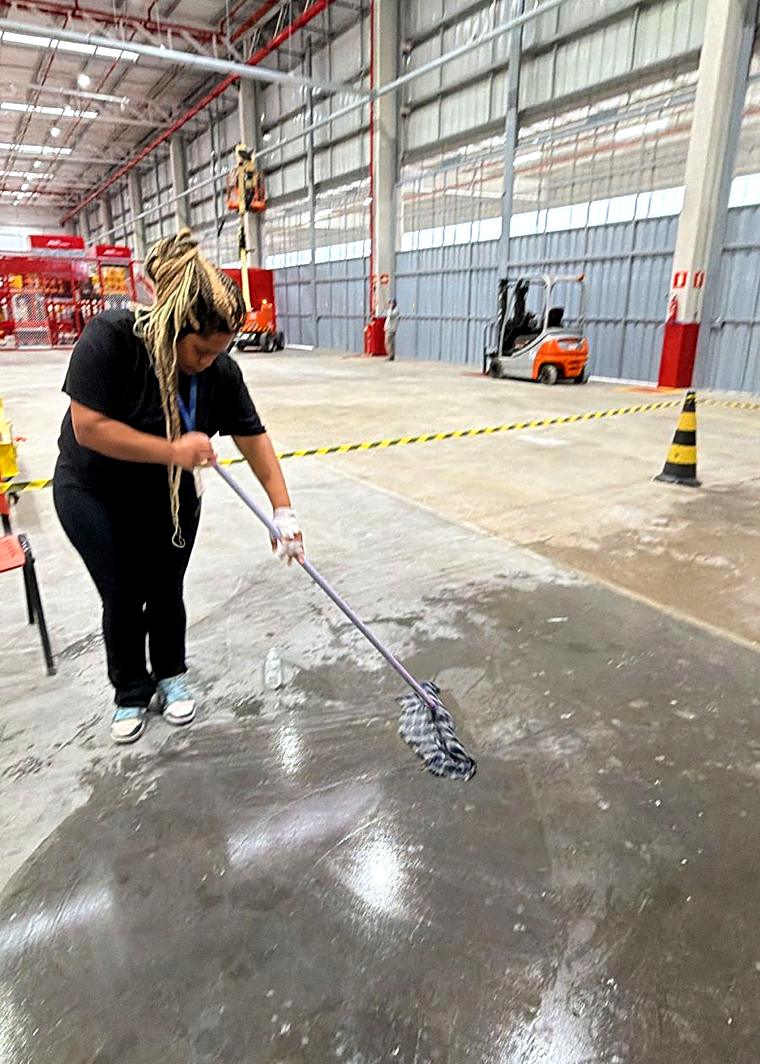 Profissional da Hello lavando piso de galpão industrial